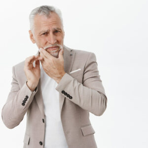 imagem de um homem de meia idade com a mão no rosto com algum problema periodontal