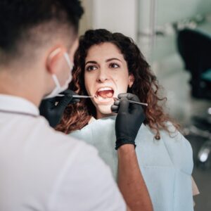 A imagem mostra um exemplo de uma mulher fazendo check-up no dentista.