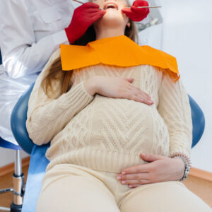 Um dentista profissional trata e examina a cavidade oral de uma mulher grávida em um consultório odontológico moderno.
