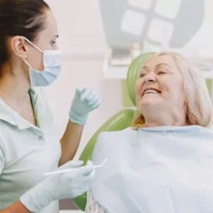 imagem de uma mulher idosa junto com a dentista vendo seu implante dentário