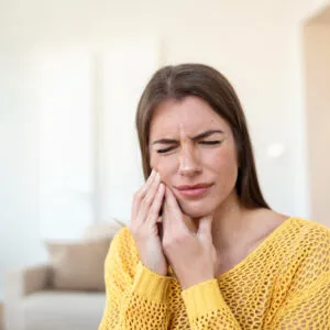 A imagem mostra uma mulher com dor de dente